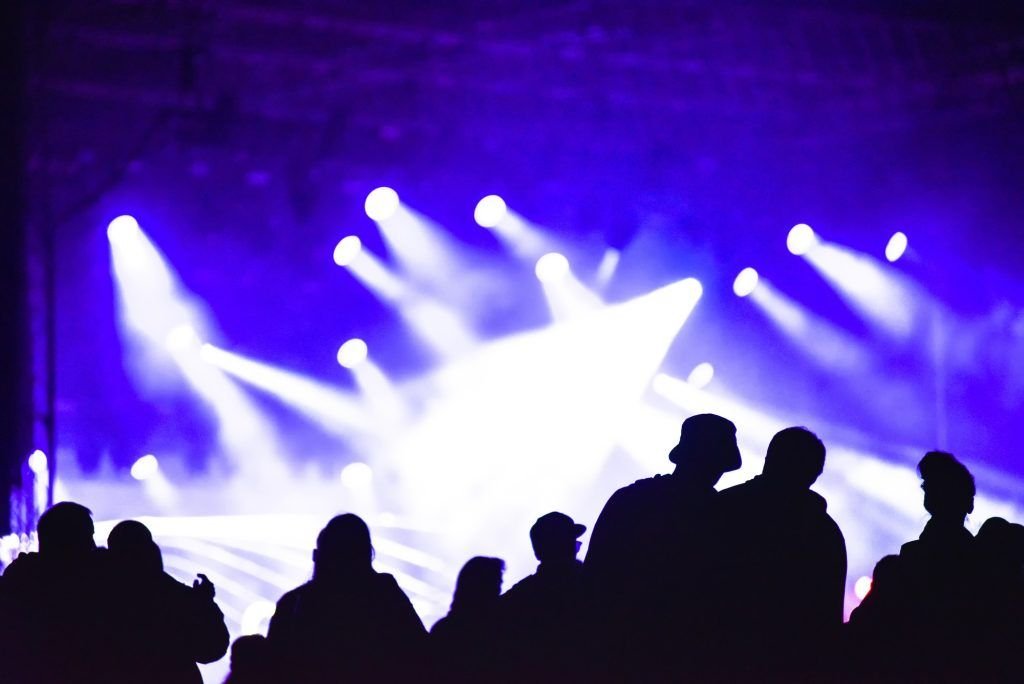 Cheerful crowd partying at a concert. Silhouette of friends socializing at a festival
